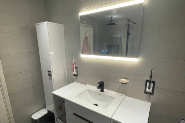 Photo of a new, white, modern bathroom that's been fitted in Southampton. Light up mirror and white sink.