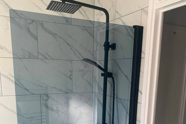 A black shower mounted on marble tiles in a bathroom.
